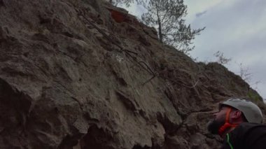 Orta yaşlı bir adam güneşli bir sonbahar gününde ferrata / klettersteig üzerinden kayaya tırmanıyor.