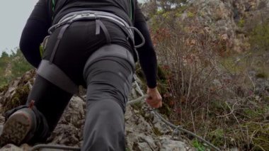 Orta yaşlı bir adam güneşli bir sonbahar gününde ferrata / klettersteig üzerinden kayaya tırmanıyor.