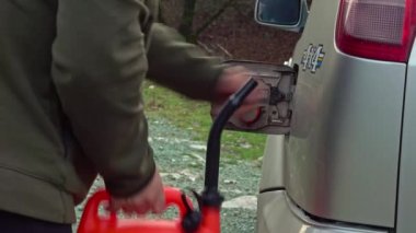 Plastik bir benzin bidonundan benzin döken bir adam. Offroad yakıt rezervi.