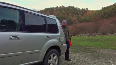 Plastik bir benzin bidonundan benzin döken bir adam. Offroad yakıt rezervi.