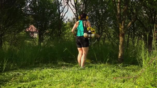 Kobieta Ścinająca Wysoką Trawę Sadzie Pomocą Szczotki — Wideo stockowe