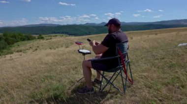 Pratik pedleri ve kulaklıkları olan bir sanatçı, yaz otlaklarında dışarıda pratik yapıyor. Davul çalışması