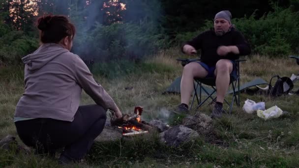男女徒步旅行者黎明时分在树林的篝火边准备食物夏夜 — 图库视频影像