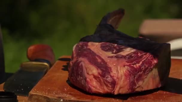 Seorang Pria Menaburkan Garam Atas Steak Mata Iga Mentah Papan — Stok Video