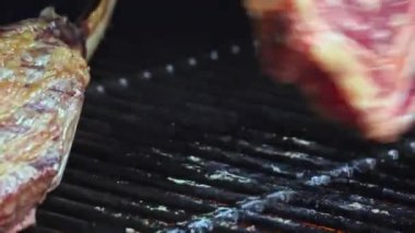 Koruyucu eldivenli adam ızgarada biftek pişiriyor.