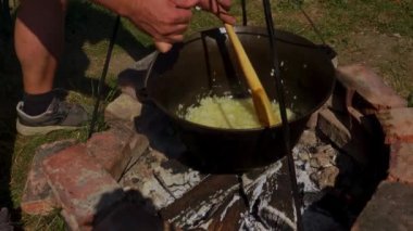 Geleneksel bir Romen yemek sahnesinde, otantik zakuska yapımında önemli bir adım olarak, odun ateşinin üzerinde soğan soteleniyor. Kırsal açık hava düzeni, bu lezzetli yayılımı yaratmak için kullanılan onurlu yöntemleri vurgular..
