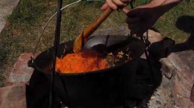 Geleneksel bir Romen yemek sahnesinde, otantik zakuska yapımında önemli bir adım olarak, odun ateşinin üzerinde soğan soteleniyor. Kırsal açık hava düzeni, bu lezzetli yayılımı yaratmak için kullanılan onurlu yöntemleri vurgular..