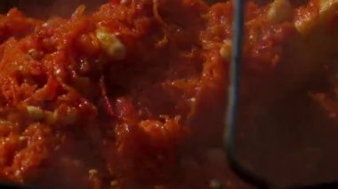 Geleneksel Romen zakuskasının ahşap bir ateşin üzerinde bir kazanda hazırlandığını gösteren kırsal bir sahne. Bu açık hava pişirme süreci doğal malzemelerin ve geleneksel yöntemlerin kullanımını vurguluyor ve bu da zengin ve lezzetli bir yayılımla sonuçlanıyor..