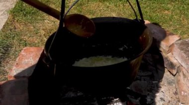 Geleneksel bir Romen yemek sahnesinde, otantik zakuska yapımında önemli bir adım olarak, odun ateşinin üzerinde soğan soteleniyor. Kırsal açık hava düzeni, bu lezzetli yayılımı yaratmak için kullanılan eski moda yöntemleri vurgular..