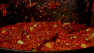 Geleneksel bir Romen yemek anı, baharatların odun ateşinin üzerinde kaynayan bir zakuska kazanına eklendiği. Bu rustik açık hava sahnesi lezzetlerin aromatik karışımını yakalar ve bu otantik yemeği yapma sürecini gözler önüne serer..