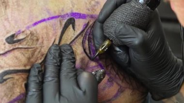 Bu büyüleyici yakın çekim ile dövmenin karmaşık dünyasına dalın. Sanatçının ellerine ve dövme makinesine odaklanan video, her bir eşsiz tasarımın yaratıcılığını ve hassasiyetini yakalıyor..