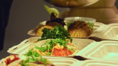 Lezzetli fast food 'un dikkatlice paketlenip bu yakın çekim videoda teslim edilmeye hazır hale getirilmesini izleyin. Kızarmış patateslerden sulu hamburgerlere ve taze kenarlara kadar her parça hassas bir şekilde yerleştirilir.. 