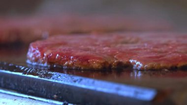 Izgarada et cızırdarken, lezzetli bir hamburger için mükemmel bir köfteye dönüşmesini izleyin. Bu yakın planda, et lezzetli, altın kahverengiye dönüşür, yağ renginde lezzetli, ağız sulandırıcı bir kabuk oluşturur.. 