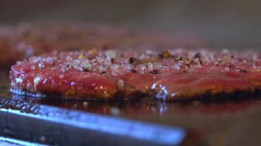 Izgarada et cızırdarken, lezzetli bir hamburger için mükemmel bir köfteye dönüşmesini izleyin. Bu yakın planda, et lezzetli, altın kahverengiye dönüşür, yağ renginde lezzetli, ağız sulandırıcı bir kabuk oluşturur.. 