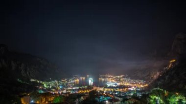 Amazing time lapse video with a night view of the picturesque Bay of Kotor with the illuminated buildings and a maneuvering cruise ship leaving the harbor.