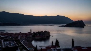 Budva Eski kenti ve Karadağ 'ın tekneli marinası üzerinde gün doğumunun inanılmaz bir videosu. Geceden güne hiperaktifleşir.