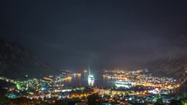 Amazing time lapse video with a night view of the picturesque Bay of Kotor with the illuminated buildings and a maneuvering cruise ship leaving the harbor.