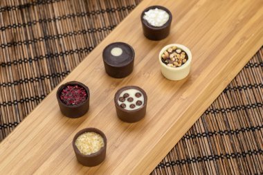 Tahta bir tahtanın üzerinde çeşitli lezzetli çikolata şekerleri bulunan çikolatalı bir cazibe. Üst görünüm.