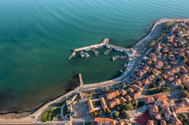 Bulgaristan 'ın Karadeniz kıyısındaki antik bir kasaba olan Nessebar' ın havadan görünüşü, kırmızı çatılı evler ve yatlı rıhtımlar ve turkuaz suların ortasında küçük tekneler.