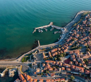 Bulgaristan 'ın Karadeniz kıyısındaki antik bir kasaba olan Nessebar' ın havadan görünüşü, kırmızı çatılı evler ve yatlı rıhtımlar ve turkuaz suların ortasında küçük tekneler.