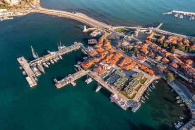 Bulgaristan 'ın Karadeniz kıyısındaki antik bir kasaba olan Nessebar' ın havadan görünüşü, kırmızı çatılı evler ve yatlı rıhtımlar ve turkuaz suların ortasında küçük tekneler.