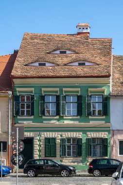 SIBIU, ROMANIA - 19 AĞUSTOS 2022: Romanya 'nın eski Sibiu kentinde göz benzeri pencereleri olan kırmızı kiremitli geleneksel ev.