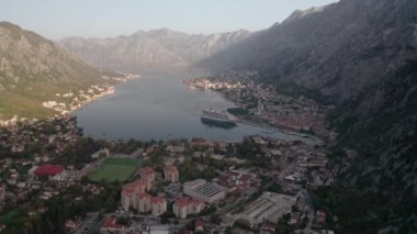 Kotor 'un (Boka Kotor) güzel kıyı şeridi, kırmızı çatıları, tekneli marinası ve Karadağ' daki büyük yolcu gemisi.