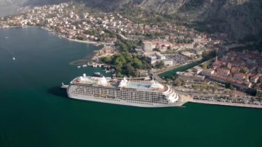 Kotor 'un (Boka Kotor) güzel kıyı şeridi, kırmızı çatıları, tekneli marinası ve Karadağ' daki büyük yolcu gemisi.