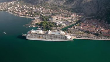 Kotor 'un (Boka Kotor) güzel kıyı şeridi, kırmızı çatıları, tekneli marinası ve Karadağ' daki büyük yolcu gemisi.