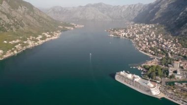Kotor 'un (Boka Kotor) güzel kıyı şeridi, kırmızı çatıları, tekneli marinası ve Karadağ' daki büyük yolcu gemisi.