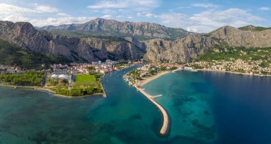 Hırvatistan 'ın görkemli Omish kasabasının panoramik manzarası, uçurumlar, kırmızı çatıları olan eski evler, tarihi binalar ve turkuaz Adriyatik Denizi' ne akan nehir