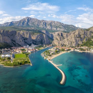 Hırvatistan 'ın görkemli Omish kasabasının panoramik manzarası, uçurumlar, kırmızı çatıları olan eski evler, tarihi binalar ve turkuaz Adriyatik Denizi' ne akan nehir