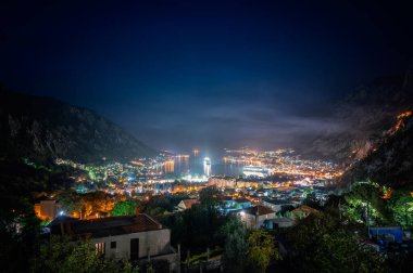 Limandaki aydınlık sokakları, binaları ve yolcu gemileriyle Kotor Körfezi 'nin muhteşem gece manzarası..