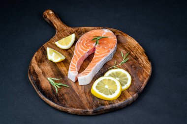 Tahtaya dizilmiş limon ve biberiyeli taze çiğ somon dilimi. Sağlıklı deniz ürünleri. Üst görünüm.