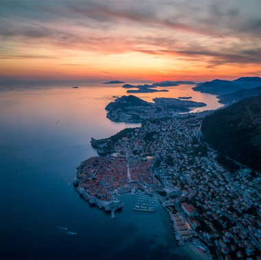 Eski kasaba Dubrovnik 'in muhteşem manzarası, aydınlanmış sokaklar, binalar ve yanan günbatımında tekneleri olan marina..