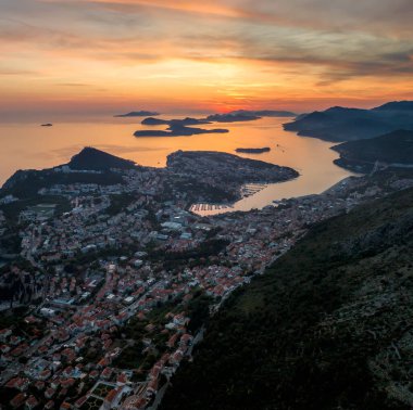 Eski kasaba Dubrovnik 'in muhteşem manzarası, aydınlanmış sokaklar, binalar ve yanan günbatımında tekneleri olan marina..