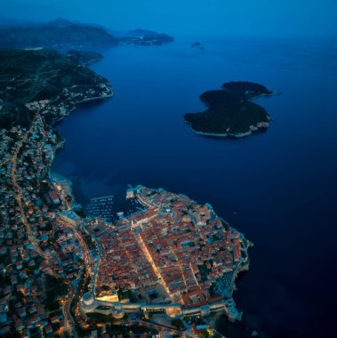 Eski kasaba Dubrovnik 'in muhteşem manzarası, aydınlanmış sokaklar, binalar ve marina gün batımından bir saat sonra teknelerle aydınlanıyor..