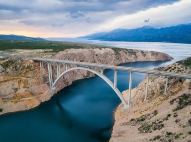 Hırvatistan 'ın Zadar kenti yakınlarındaki bir güverte kemeri olan Maslenica köprüsü ile hava panoramik manzarası güzel bulutlar ve canlı denizlerle dolu