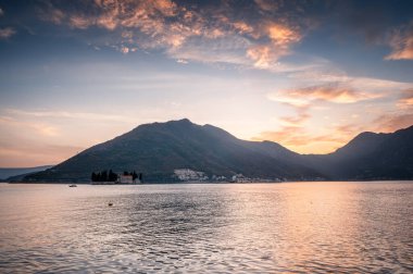 Karadağ 'ın gün batımının altın saatinde, güzel Perast kasabası ve adaları yakınlarındaki Kotor Körfezi' nin manzaralı uçurumlarının panoramik manzarası.