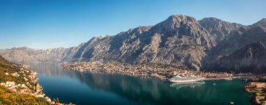 Kotor 'un güzel kıyı şeridi, gezinti güvertesi, kırmızı çatıları, tekneli marina ve Karadağ' daki büyük yolcu gemisinin hava panoramik manzarası