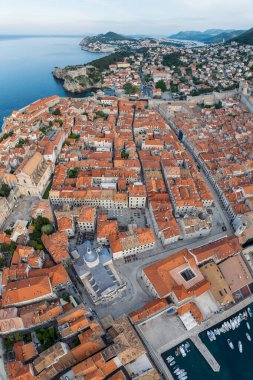 Eski kenti, dar taş caddeleri ve kırmızı çatıları olan binaları, Adriyatik deniz kıyısında tekneleri olan marinaları olan manzaralı Dubrovnik kentinin hava panoramik manzarası, Hırvatistan.