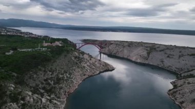 Hırvatistan 'ın Zadar kenti yakınlarında Adriyatik Denizi üzerinde güzel bulutlar bulunan bir güverte kemer köprüsü olan Maslenica köprüsü ile hava panoramik videosu
