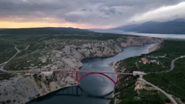 Hırvatistan 'ın Zadar kenti yakınlarında Adriyatik Denizi üzerinde güzel bulutlar bulunan bir güverte kemer köprüsü olan Maslenica köprüsü ile hava panoramik videosu