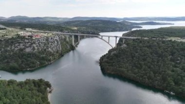 Hırvatistan 'ın Adriyatik kıyısındaki İbenik kasabası yakınlarındaki güzel bir güverte kemer köprüsünün hava panoramik videosu.