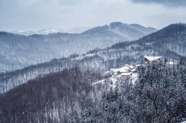 Karla kaplı tepelerin arasına kurulmuş küçük bir köyle harika bir kış manzarası.
