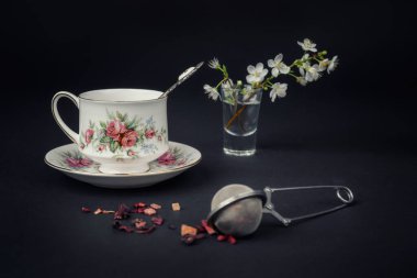 Güzel bir porselen çay fincanı ve siyah arka planda çay aksesuarları ile sakin bir hayat.
