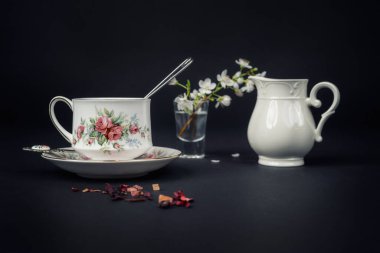 Güzel bir porselen çay fincanı ve siyah arka planda çay aksesuarları ile sakin bir hayat.