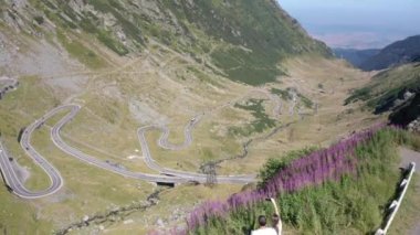Romanya 'daki ünlü Transfagarasan dağ yoluna bakan bir adam ve kadının uçurumun kenarında uçtuğu video. Doğanın güzelliğinin tadını çıkaran bir çift..