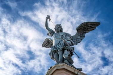 Detailed close up view of Saint Michael archangel statue with wings and sword at top of Saint Angelo castle, Rome, Italy. 	