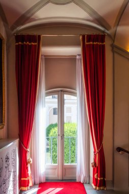 Details from the sumptuous and rich interior in the Great Hall of the Palazzo Colonna in Rome, Italy. Tall balcony door with heavy red curtains clipart